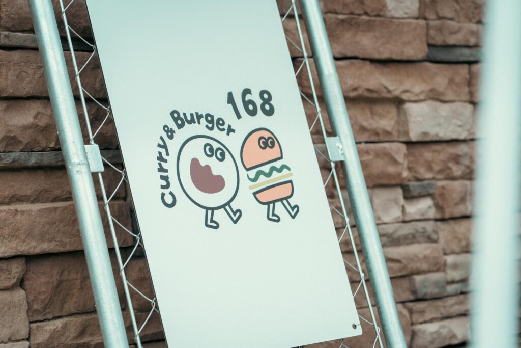 カレーとバーガーをモチーフにしたオリジナルキャラクターの店名ロゴ。SNSでも話題のかわいさ