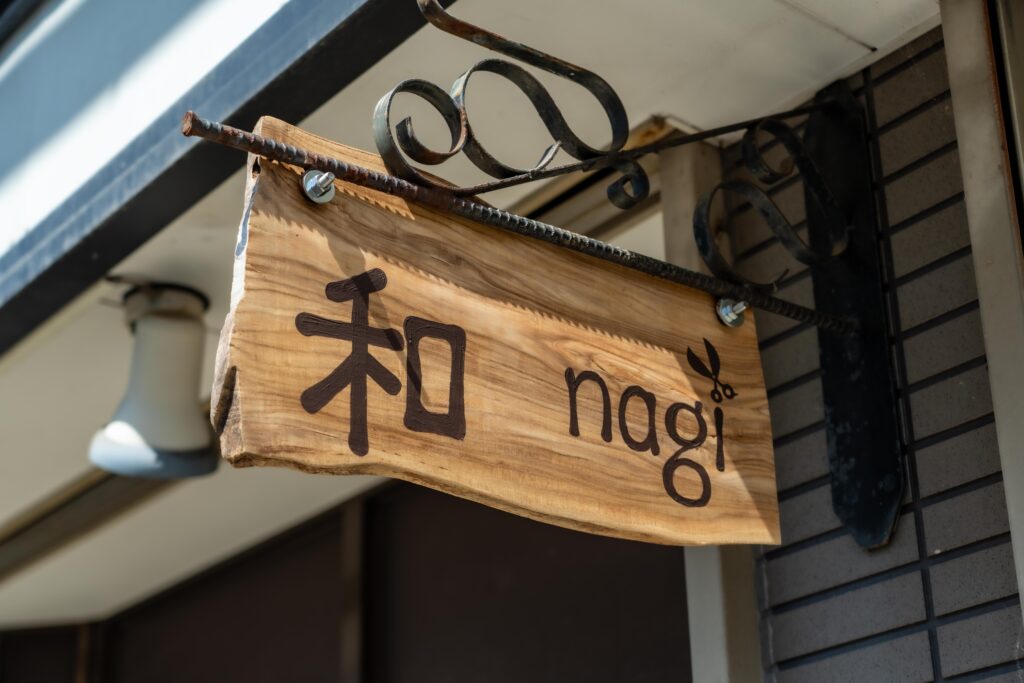 南魚沼市のカット専門店「カットハウス和〜nagi〜」の木製看板。ナチュラルであたたかみのあるデザインが特徴。