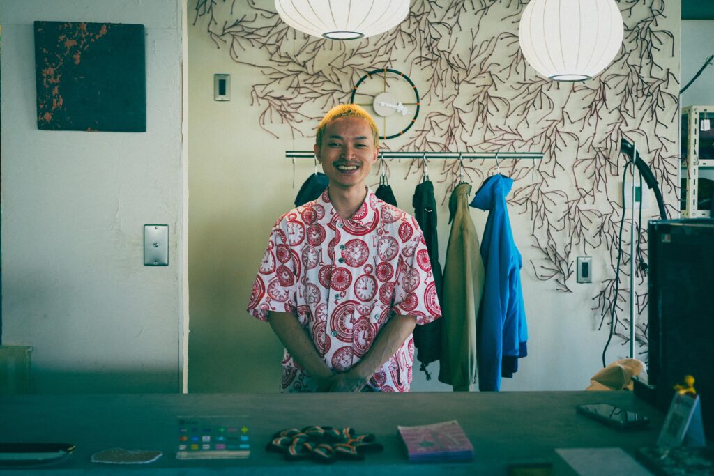 エントランスで来店者を迎えるオーナー町田さん。壁のアートも印象的なカウンター前