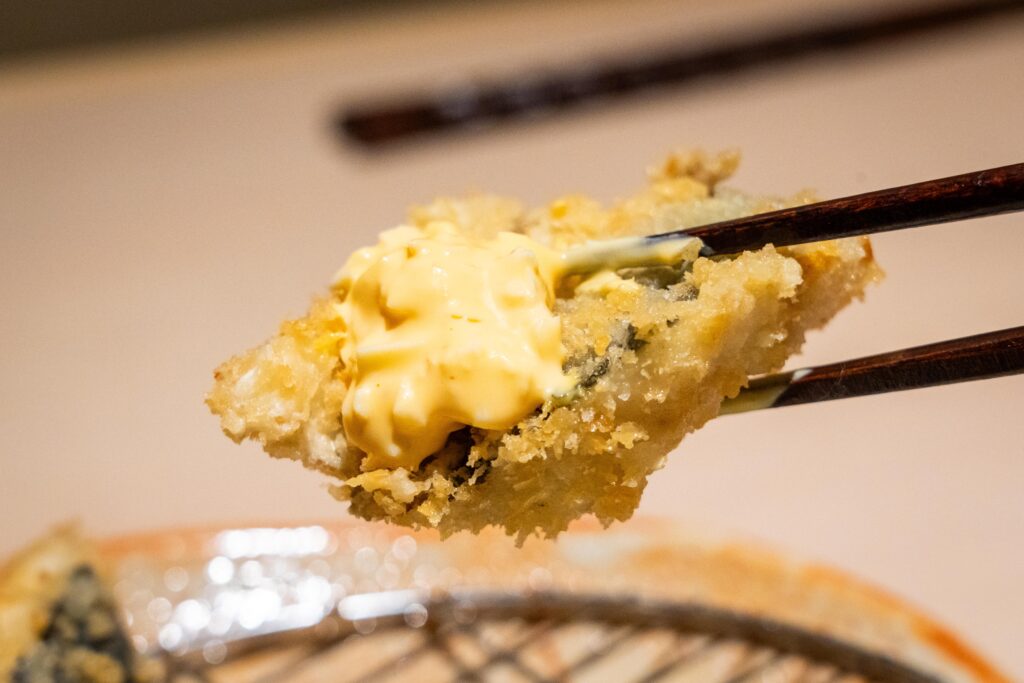アジフライの断面アップ。外はザクッ、中はふわふわの食感が伝わるカット。
