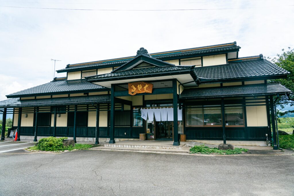 黒とベージュの外観が印象的な『そば処 富永』の店舗外観。風格ある日本建築と「そば処」の看板が来店者を迎える。
