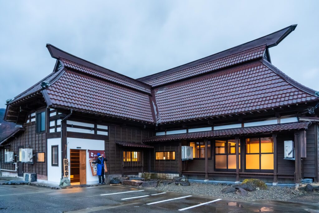 南魚沼市上一日市に立つ「こめのすけ」の古民家外観。赤い瓦屋根が特徴的な、雪国らしい温かみのある建物。