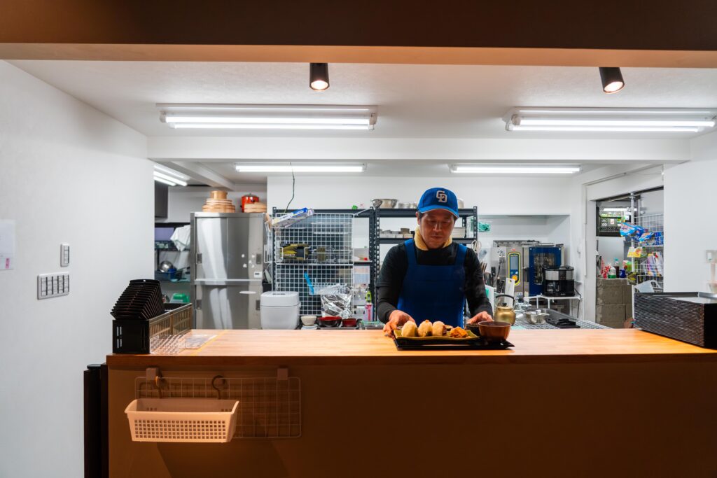 南魚沼市「こめのすけ」で、コシヒカリのおむすびを盛り付ける店主・入田啓輔さん。農家が手掛ける丁寧な調理風景。