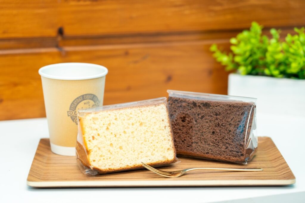 木製トレーに乗った個包装の米粉シフォンケーキとホットコーヒー。南魚沼産コシヒカリを使用したふわふわのグルテンフリースイーツ。