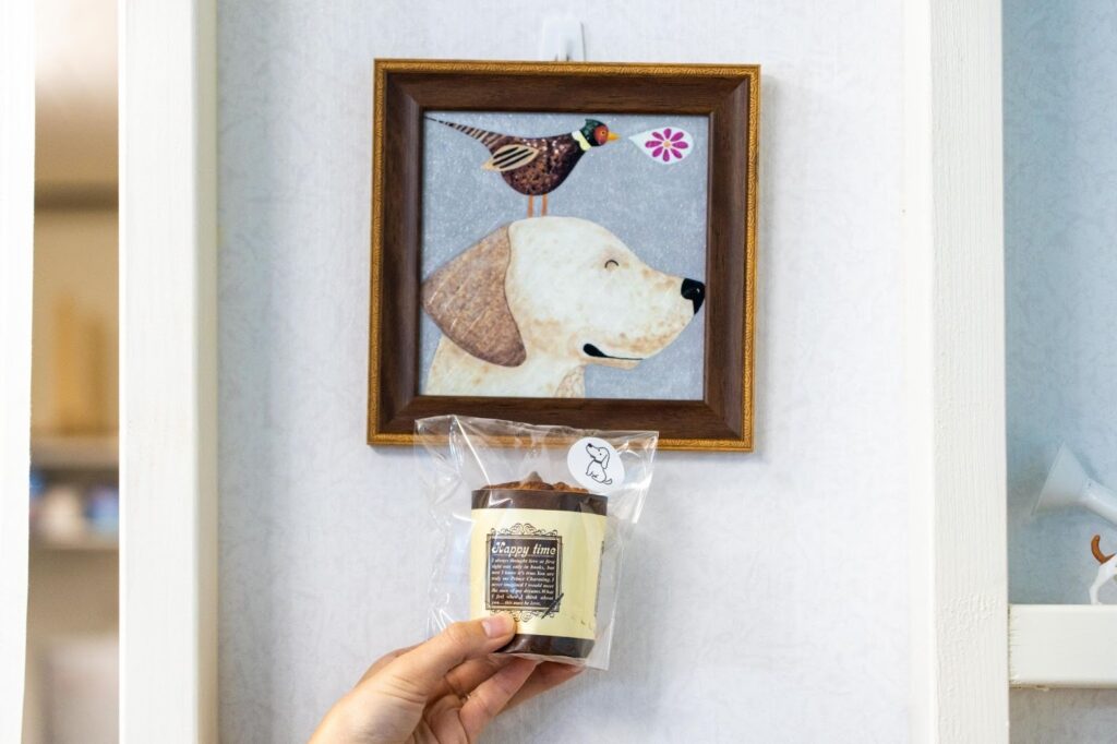 わんちゃんも食べられるノンシュガーの米粉シフォンケーキと、壁に飾られた犬のイラスト。ドッグフレンドリーな店内の様子。